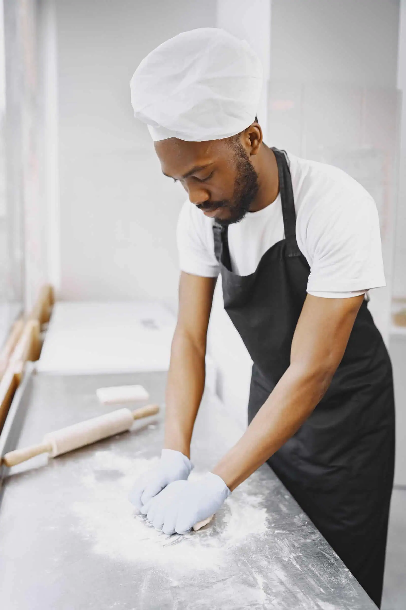 Baker kneading dough in a small bakery kitchen