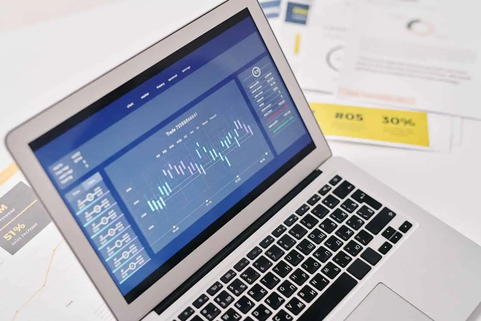 Laptop beside printed documents on a desk, checking facts before publishing a web page