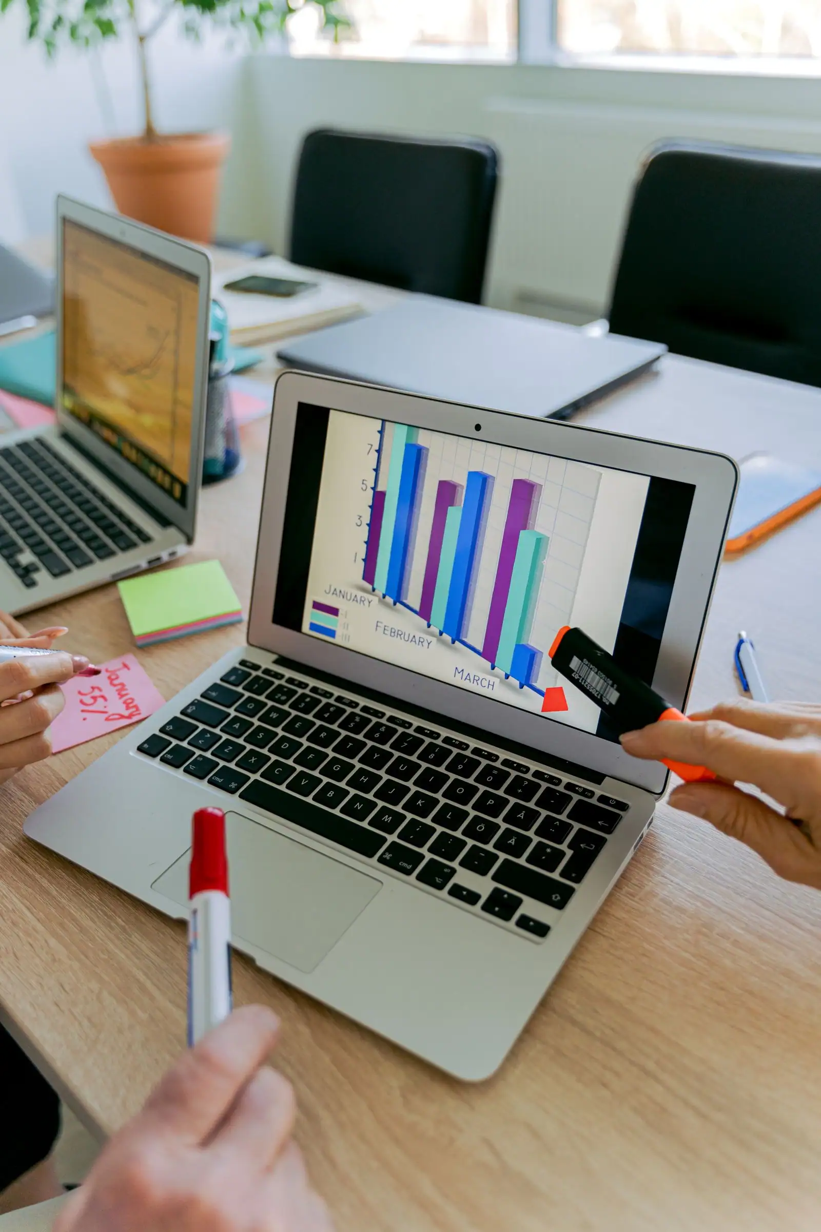 Team reviewing a bar chart of monthly results on a laptop screen