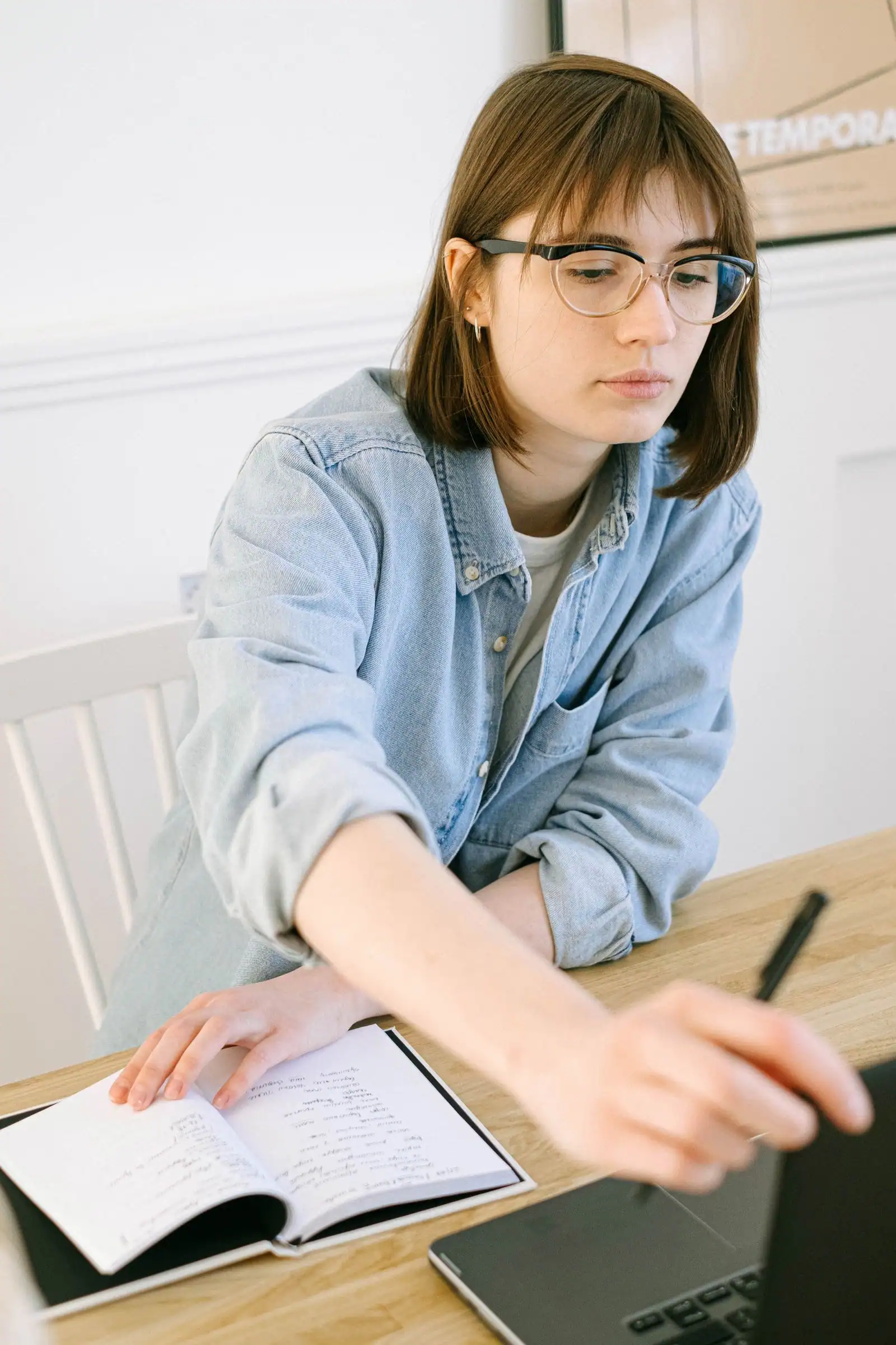 Woman taking notes beside a laptop while planning a how-to guide