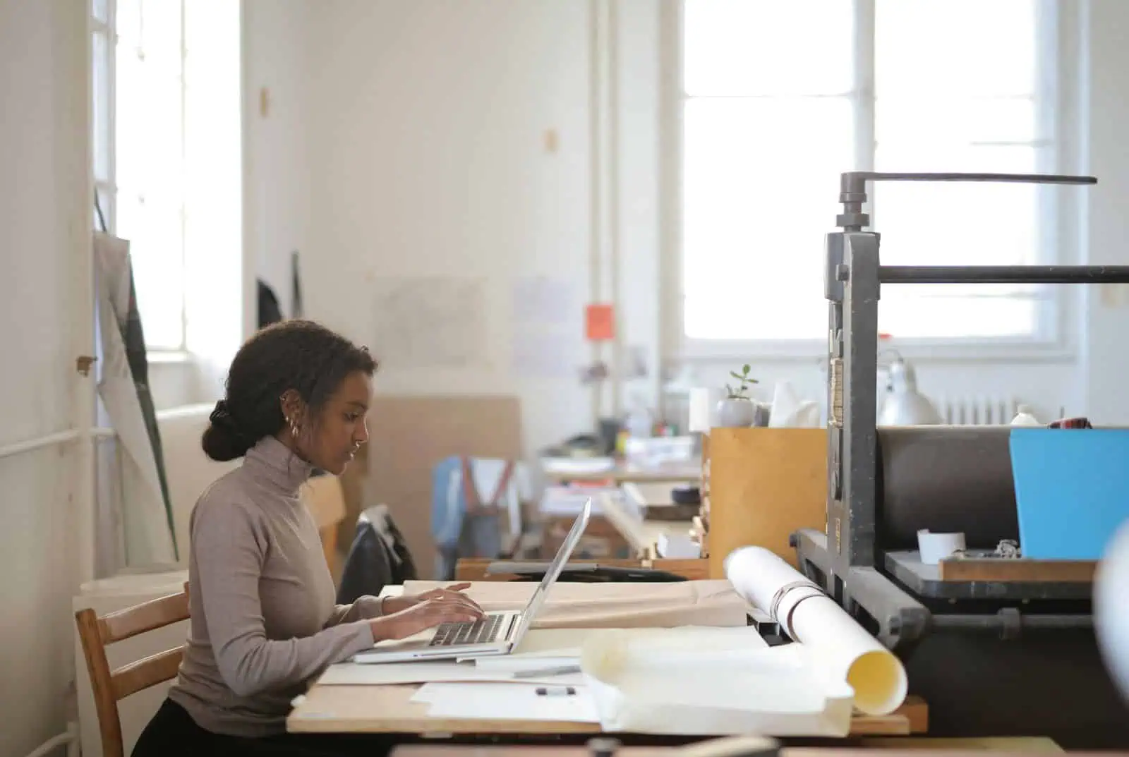 Woman working on a laptop, using AI tools to research topics for her business website